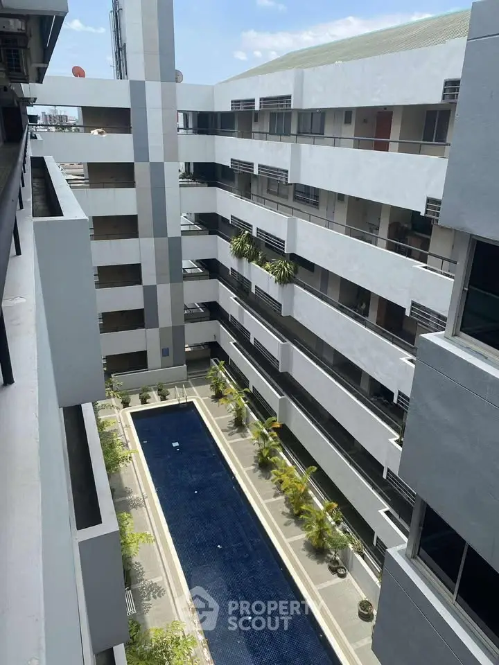 Modern apartment building with central courtyard pool and lush greenery.