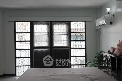 Spacious bedroom with large windows and air conditioning unit, ideal for comfort and relaxation.