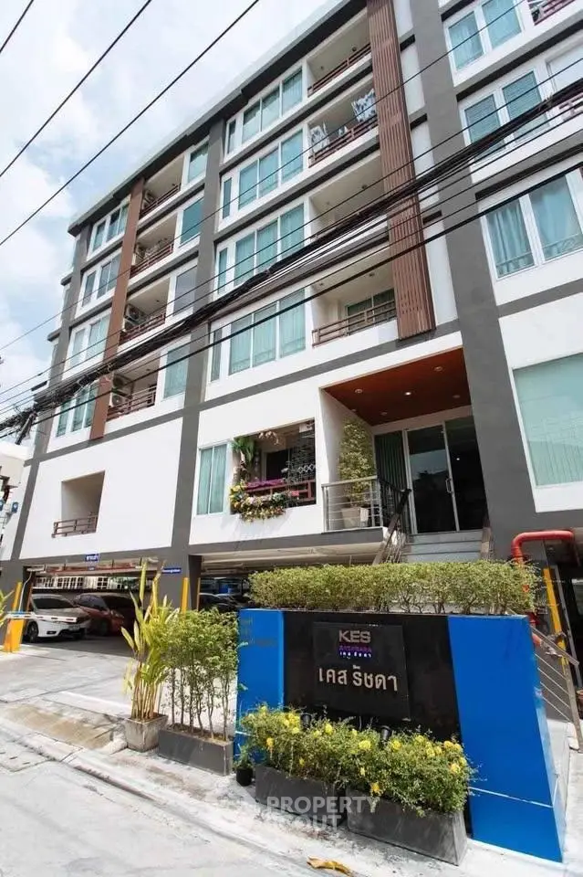 Modern multi-story apartment building with stylish facade and landscaped entrance in urban setting.
