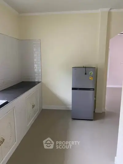 Spacious kitchen with modern fridge and ample counter space in a bright, minimalist design.