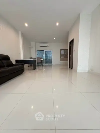 Spacious modern living room with sleek white tiles and minimalist decor, perfect for contemporary living.