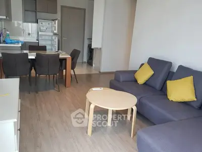 Modern living room with open kitchen, stylish furniture, and wooden flooring in a cozy apartment.