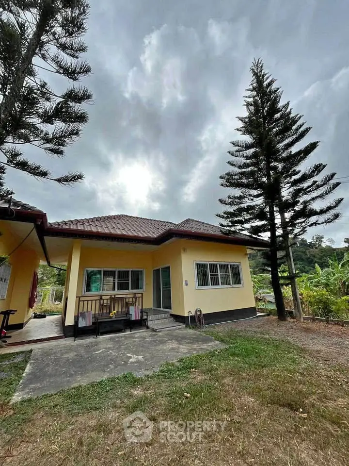Charming yellow house with lush greenery and spacious outdoor area.