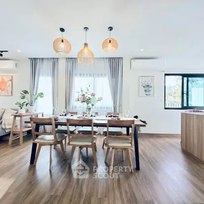 Modern dining area with elegant wooden furniture and stylish lighting in a bright open-plan living space.