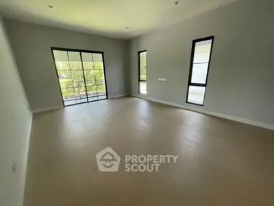 Spacious empty room with large windows and wooden flooring, perfect for customization.