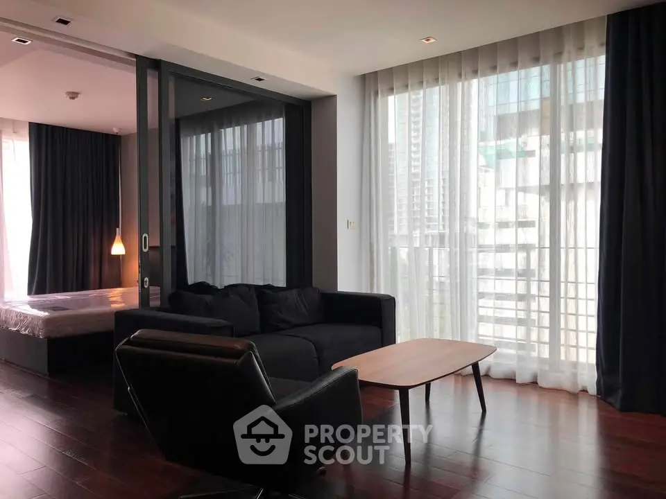 Modern living room with floor-to-ceiling windows and elegant dark furnishings in a high-rise apartment.