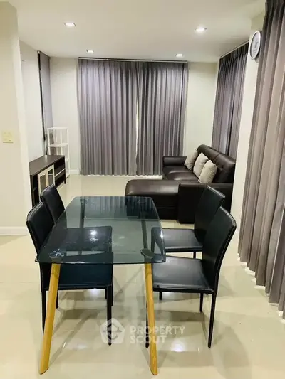 Modern living room with sleek glass dining table and cozy sofa, perfect for stylish urban living.