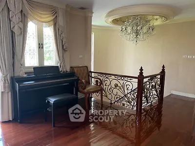 Elegant home interior with grand piano and ornate railing, featuring a luxurious chandelier and polished wooden floors.
