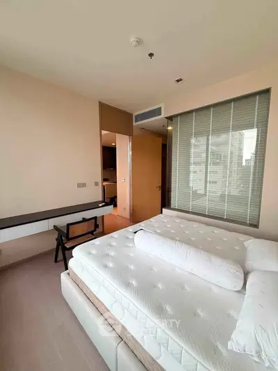 Spacious bedroom with large window and modern furnishings in a high-rise apartment.