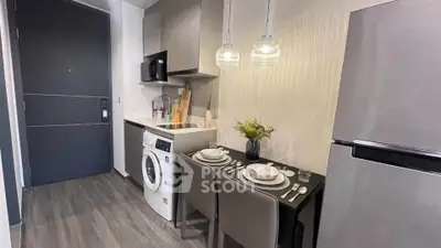 Modern compact kitchen with dining area and washing machine in stylish apartment.