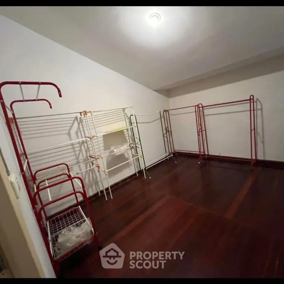 Spacious storage room with wooden flooring and multiple racks for organization.