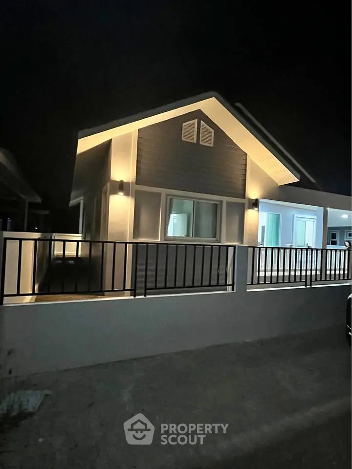 Charming modern house exterior with ambient lighting at night, featuring sleek design and inviting atmosphere.