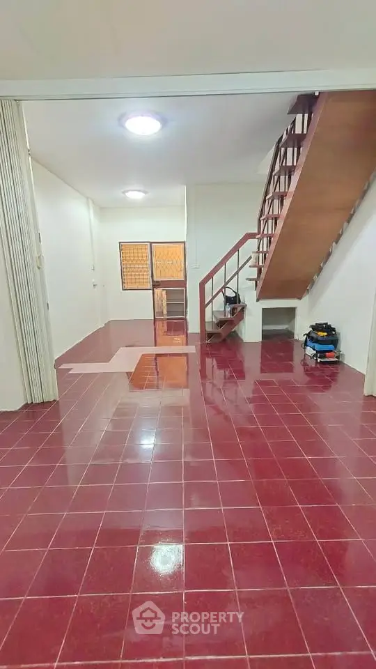 Spacious interior with red tiled flooring and wooden staircase, ideal for modern living.