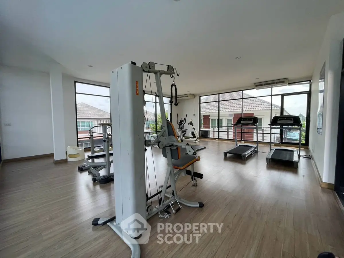 Spacious gym with modern equipment and large windows offering a bright and airy workout environment.