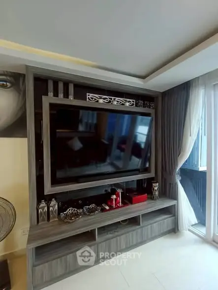 Modern living room with large TV and stylish decor in a bright apartment.