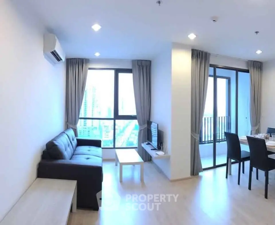 Spacious modern living room with large windows and balcony view in a high-rise apartment.