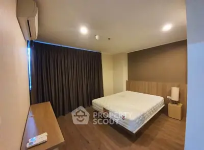 Spacious bedroom with modern decor and large window in a stylish apartment.