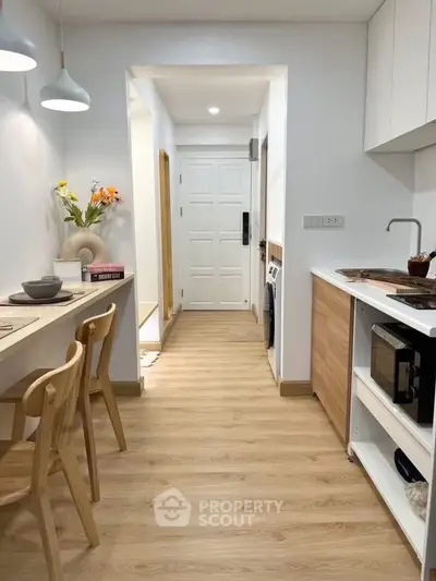 Modern kitchen with wooden flooring and open layout, featuring sleek appliances and stylish lighting.