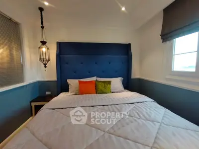 Charming bedroom with elegant blue headboard and colorful pillows, perfect for cozy living.