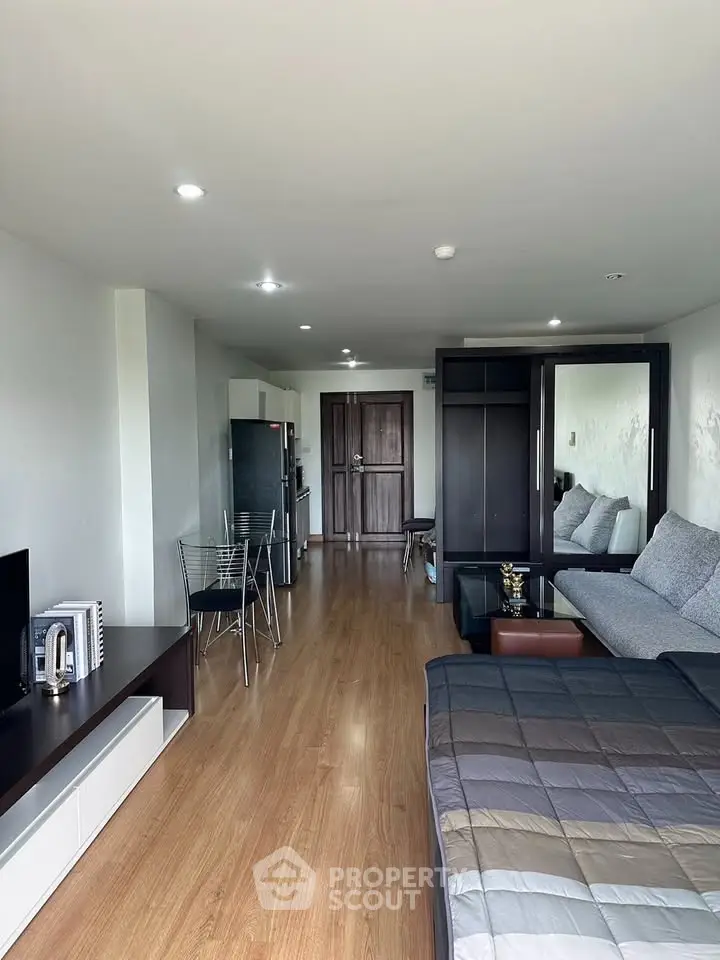 Spacious studio apartment with modern furnishings and wooden flooring, featuring a cozy living area and dining space.