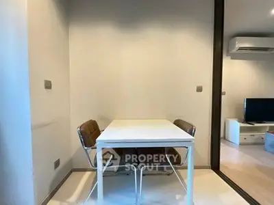 Modern minimalist dining area with sleek table and chairs, adjacent to a cozy living room with air conditioning.