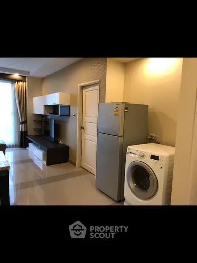 Modern living room with sleek furniture and appliances, including fridge and washing machine.