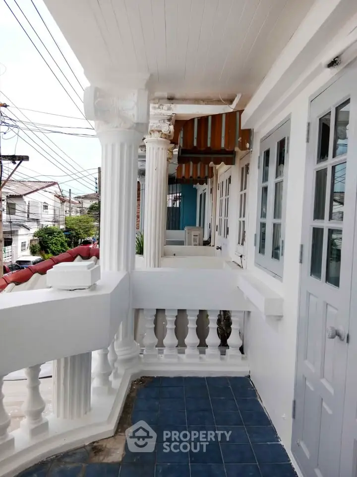 Charming colonial-style balcony with elegant columns and blue tile flooring