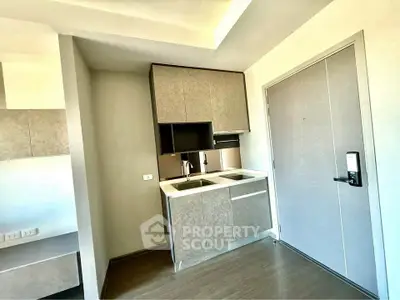 Modern compact kitchen with sleek cabinetry and dual sinks in a bright apartment.