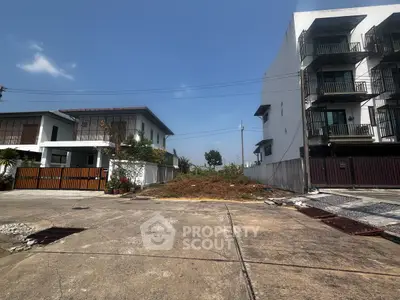 Vacant lot between modern residential buildings, ideal for new construction in a prime urban location.