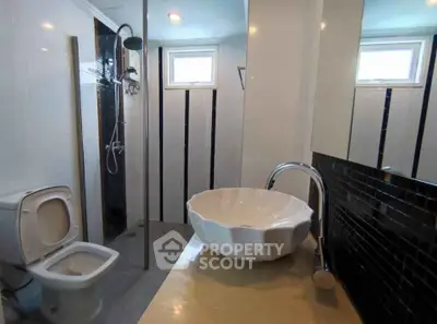Modern bathroom with unique sink and shower area in stylish apartment.