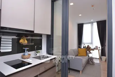 Modern apartment with sleek kitchen and cozy living area, featuring large windows and stylish decor.