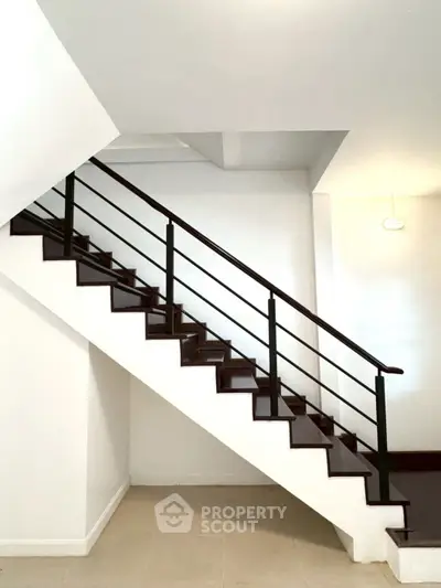 Modern staircase with sleek railing in a bright, minimalist interior space.