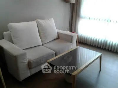 Cozy living room with modern sofa and glass coffee table, perfect for relaxation.