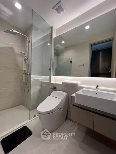 Modern bathroom with glass shower and sleek fixtures in a contemporary apartment.
