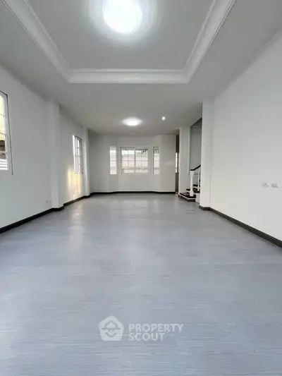 Spacious empty living room with modern flooring and ample natural light, perfect for customization.