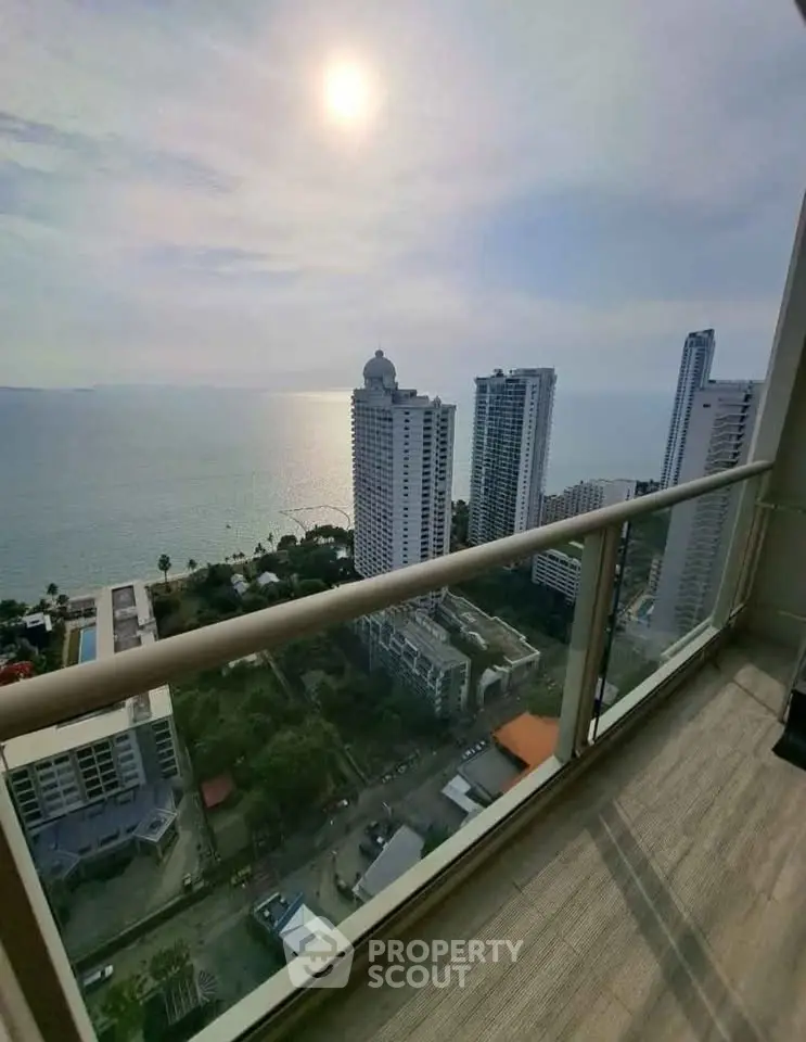 Stunning high-rise balcony view overlooking ocean and cityscape at sunset.