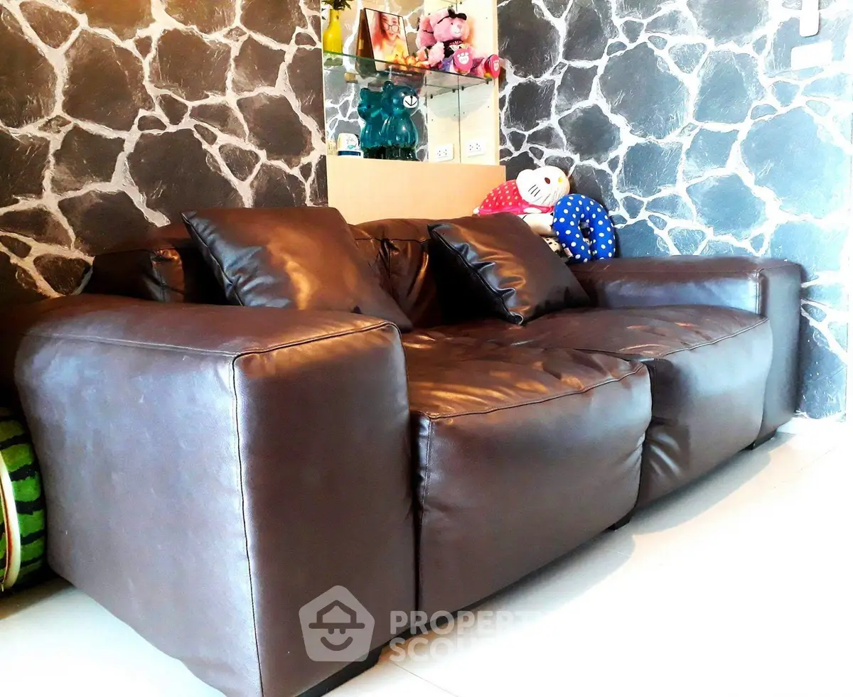 Stylish living room with a modern brown leather sofa and decorative stone wall.