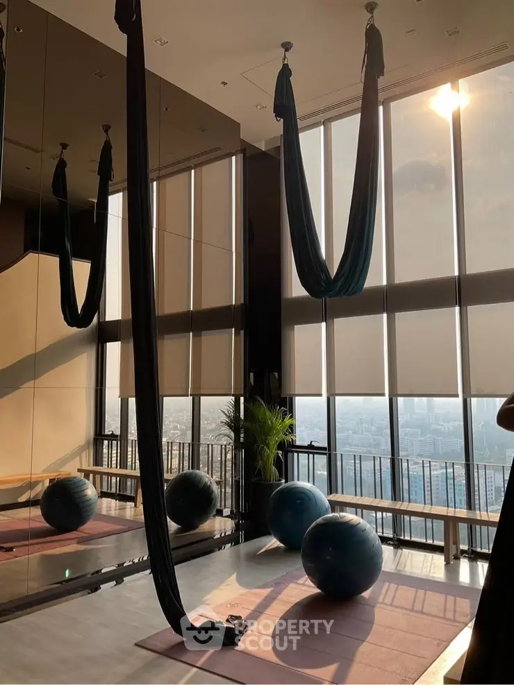 Luxurious gym with aerial yoga setup and stunning city view