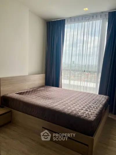 Modern bedroom with large window offering stunning city views and elegant decor.