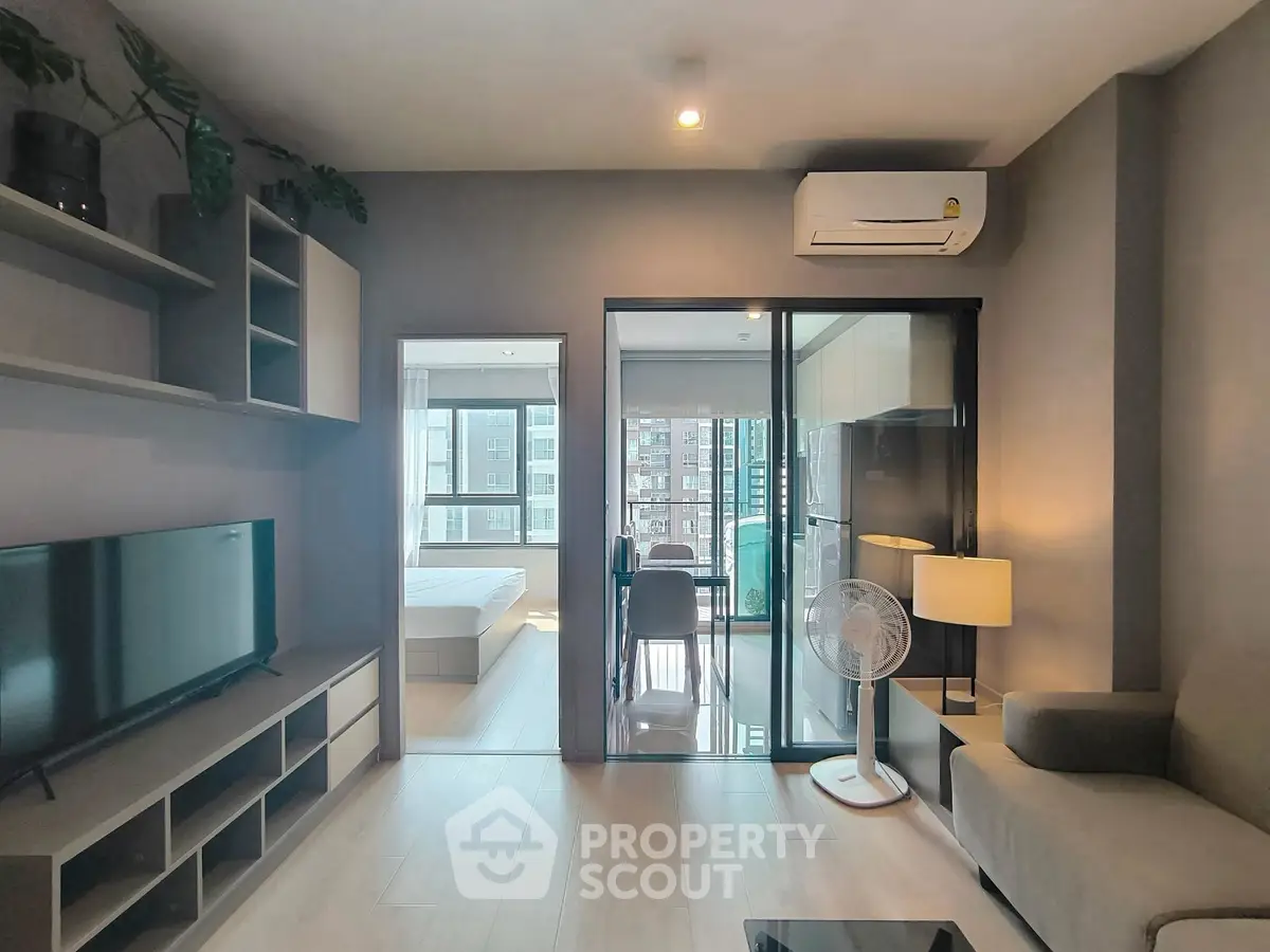 Modern living room with sleek design and open view to bedroom and kitchen.