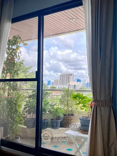 Charming balcony view with lush greenery and cityscape backdrop, perfect for relaxation.