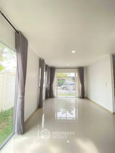 Spacious living room with large windows and elegant curtains, offering a bright and airy atmosphere.