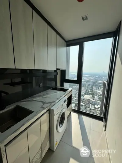 Sleek high-rise kitchen with modern appliances and marble countertops, boasting panoramic city views through floor-to-ceiling windows.