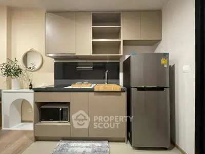 Modern kitchen with sleek cabinetry, stainless steel fridge, and built-in microwave in a stylish apartment.