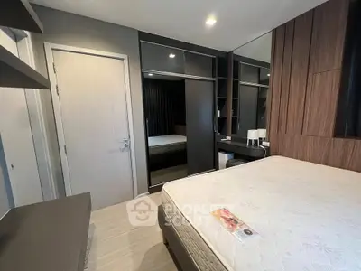 Modern bedroom with sleek design and mirrored wardrobe in a stylish apartment.