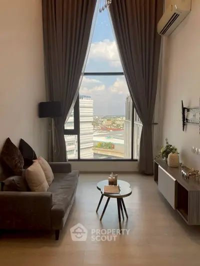 Modern living room with large window offering stunning city view, elegant decor, and cozy seating area.