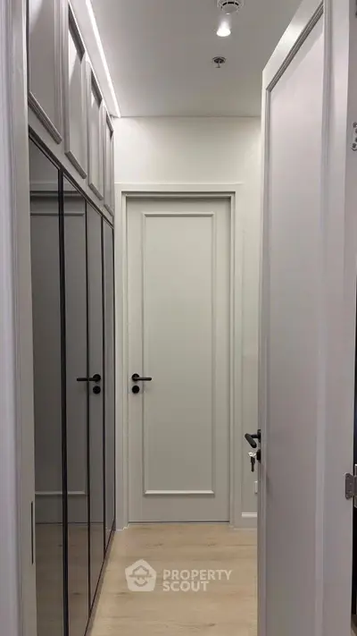 Modern hallway with sleek mirrored closets and elegant white doors in a contemporary apartment.
