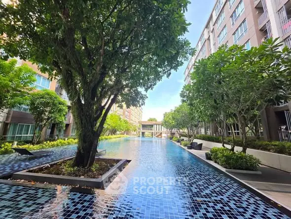 Luxurious condominium pool area with lush greenery and modern design.