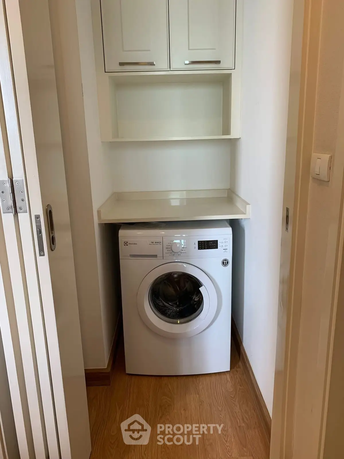Compact laundry nook with washing machine and storage cabinets in modern apartment.