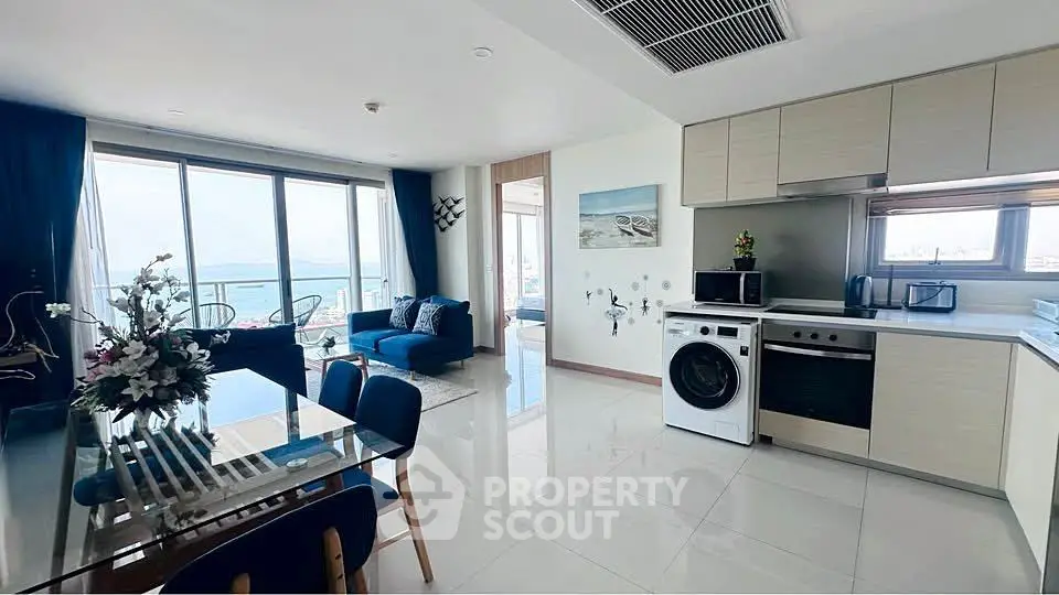 Modern open-plan living room and kitchen with ocean view and stylish decor.